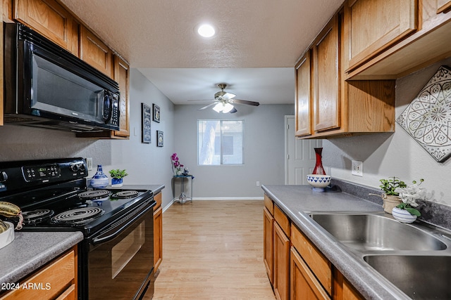 kitchen with a textured ceiling, black appliances, light hardwood / wood-style flooring, ceiling fan, and sink