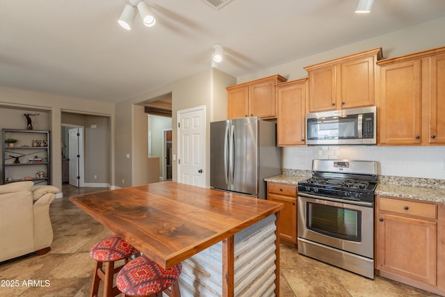 kitchen featuring appliances with stainless steel finishes, tasteful backsplash, and light stone counters
