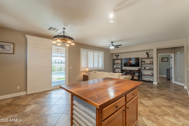 kitchen featuring wooden counters, ceiling fan, pendant lighting, and baseboards