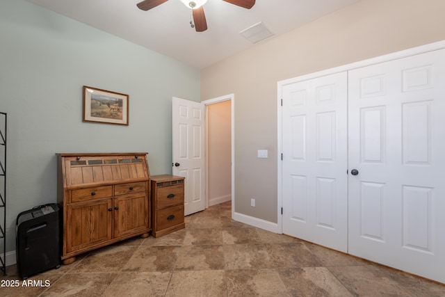 bedroom with light stone finish flooring, baseboards, ceiling fan, and a closet