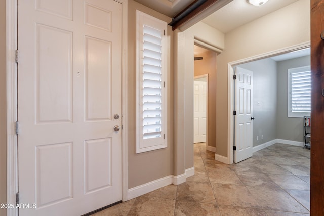 foyer entrance featuring baseboards and light stone finish floors