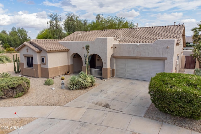 view of front of home with stucco siding, a tiled roof, concrete driveway, an attached garage, and fence