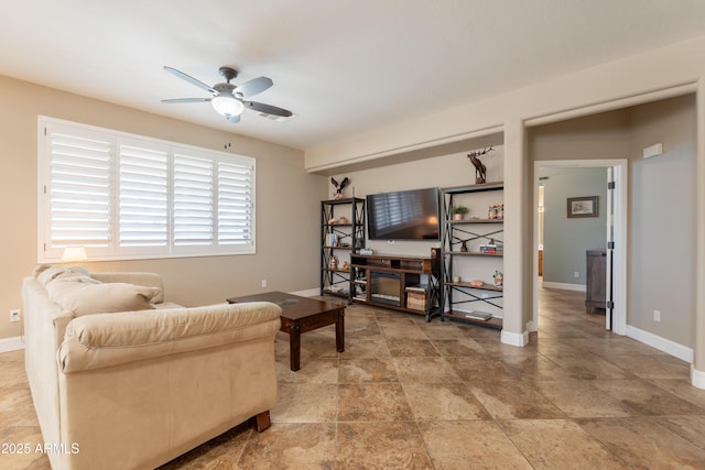 living area with a ceiling fan and baseboards