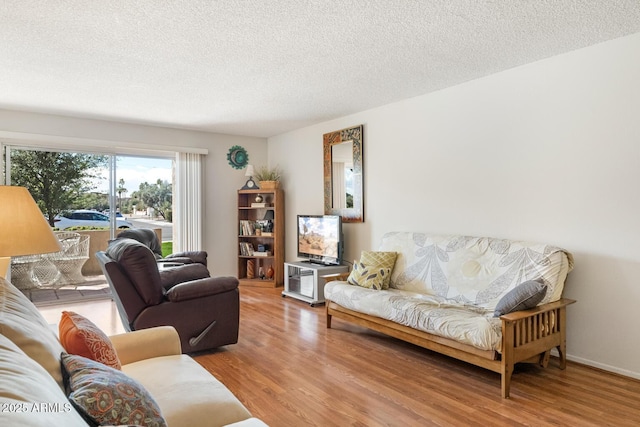 living room with a textured ceiling, baseboards, and wood finished floors