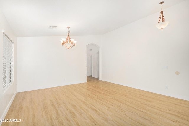 29900 N Maravilla Dr, San Tan Valley, AZ 85143 - unfurnished room with visible vents, light wood finished floors, baseboards, arched walkways, and a notable chandelier