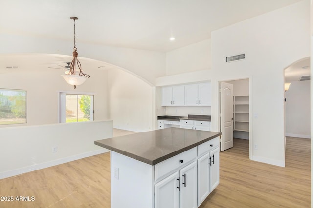 29900 N Maravilla Dr, San Tan Valley, AZ 85143 - kitchen with visible vents, arched walkways, white cabinetry, dark countertops, and light wood-type flooring