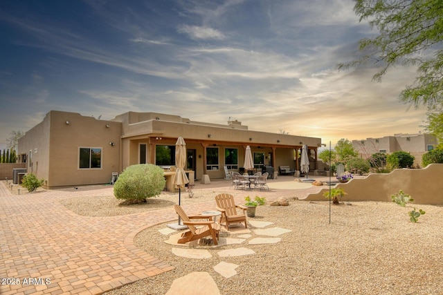 rear view of house featuring fence, central AC unit, stucco siding, and a patio area