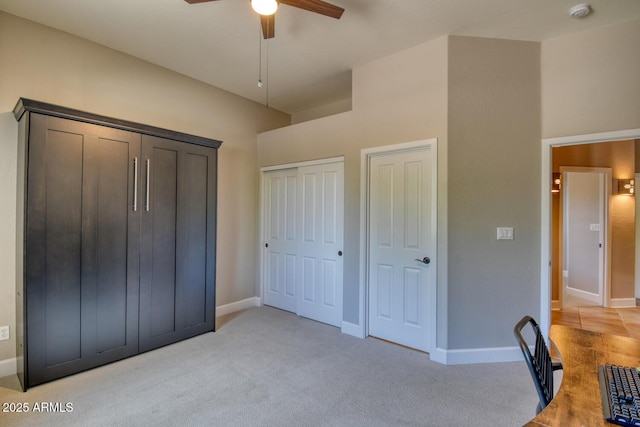 unfurnished bedroom with two closets, a ceiling fan, baseboards, and light colored carpet