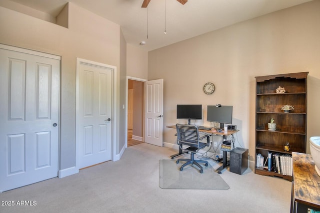 office space featuring carpet floors, ceiling fan, baseboards, and a high ceiling