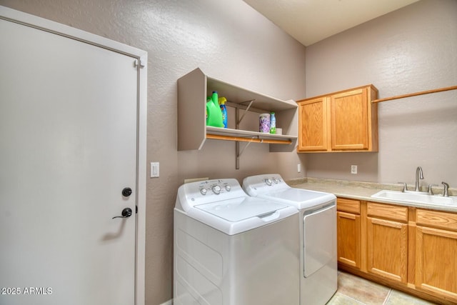 laundry room with washing machine and dryer, cabinet space, a sink, light tile patterned floors, and a textured wall