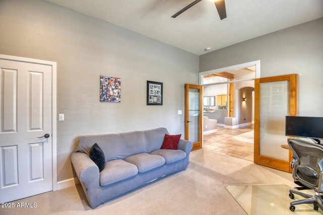home office featuring baseboards, light colored carpet, arched walkways, french doors, and a ceiling fan