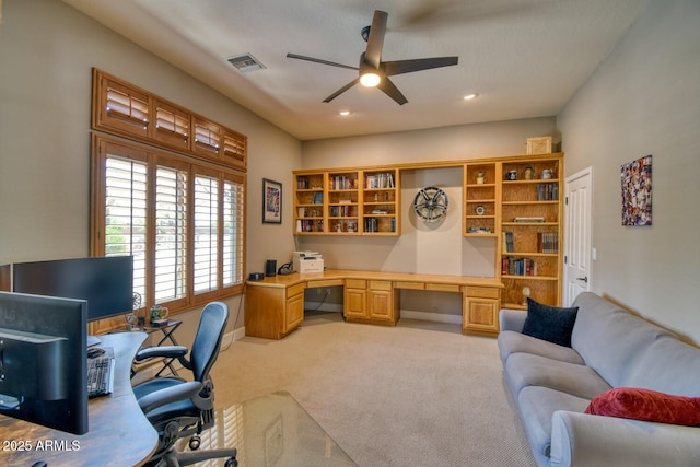 office space with visible vents, recessed lighting, light colored carpet, built in desk, and a ceiling fan