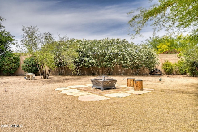 view of yard with fence and an outdoor fire pit