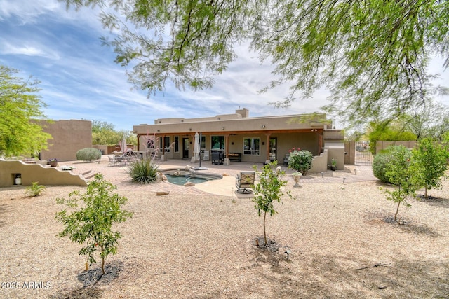 rear view of house with fence, stucco siding, a fenced in pool, a gate, and a patio