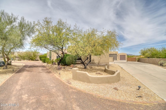 view of front of home featuring stucco siding, fence, driveway, and a garage