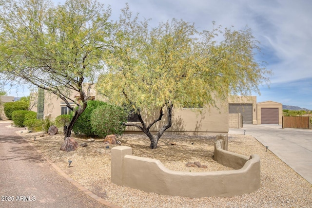 view of front of home featuring fence, driveway, and stucco siding
