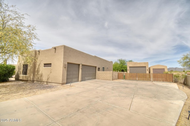 view of home's exterior featuring a garage, fence, stucco siding, and a gate