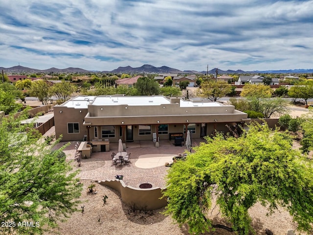 back of property featuring fence, a residential view, stucco siding, a mountain view, and a patio area