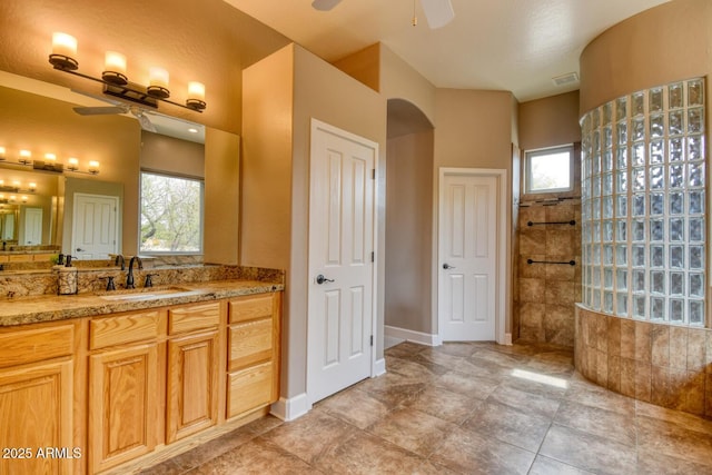 bathroom featuring vanity, a ceiling fan, a walk in shower, and visible vents