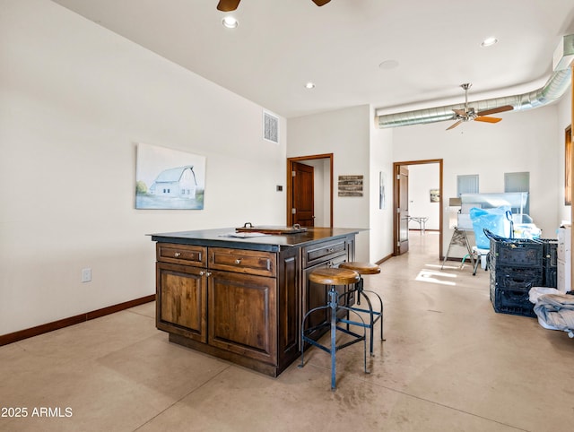 kitchen featuring a kitchen breakfast bar, ceiling fan, and a kitchen island