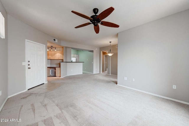 unfurnished living room featuring a ceiling fan, light carpet, and baseboards