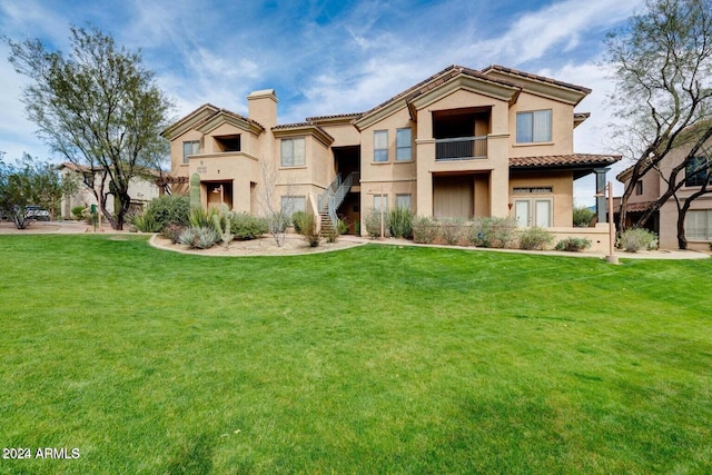 mediterranean / spanish house featuring stairs, a chimney, a front lawn, and stucco siding