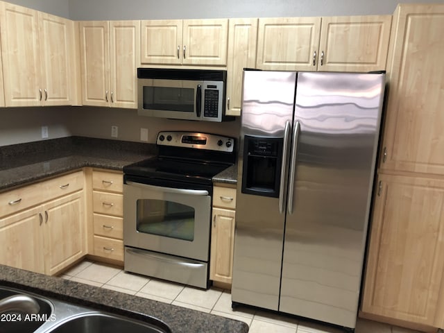 kitchen with stainless steel appliances, dark countertops, and light tile patterned floors