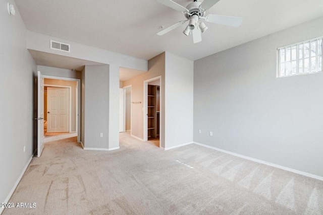 unfurnished bedroom with ceiling fan, light colored carpet, visible vents, baseboards, and a spacious closet