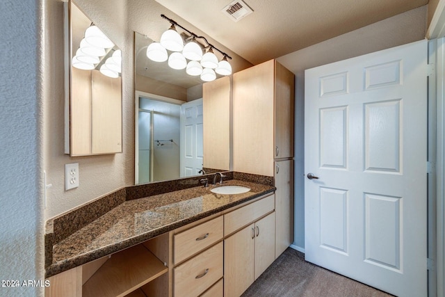 bathroom featuring a textured wall, visible vents, and vanity