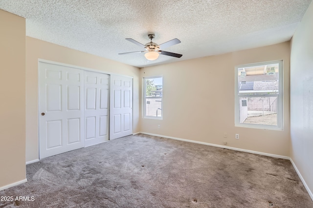 unfurnished bedroom featuring carpet flooring, a closet, ceiling fan, baseboards, and a textured ceiling