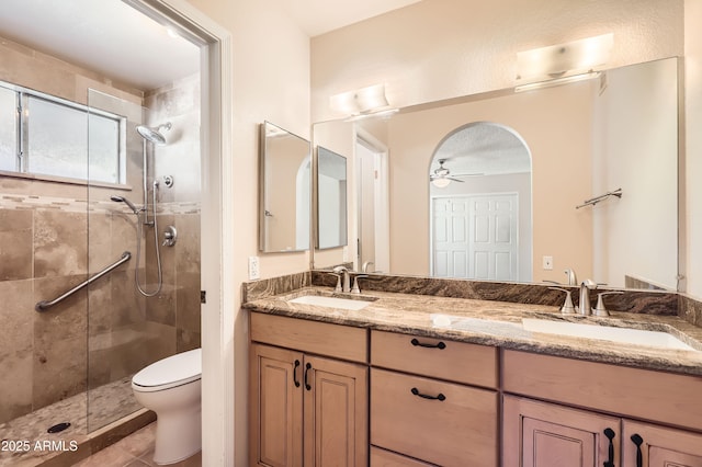 bathroom with a shower stall, a ceiling fan, toilet, and a sink