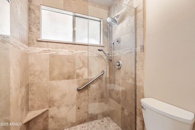 bathroom featuring tiled shower and toilet