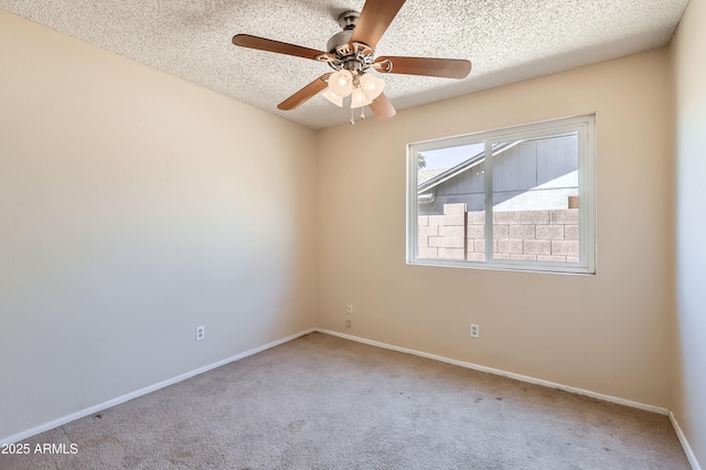 carpeted spare room with a textured ceiling, ceiling fan, and baseboards