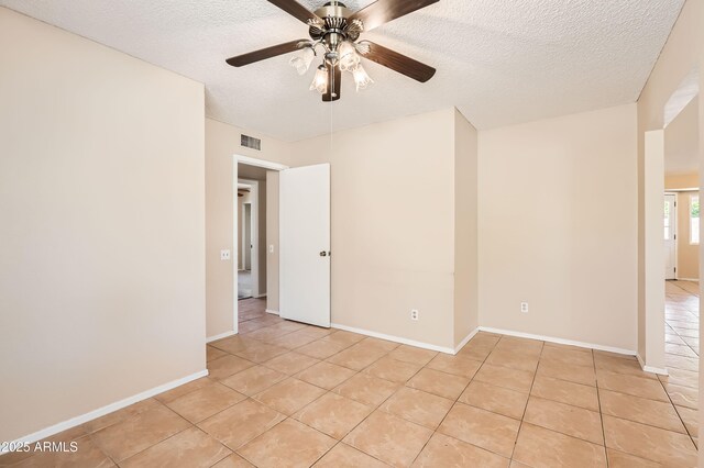 unfurnished room with visible vents, light tile patterned floors, ceiling fan, and a textured ceiling