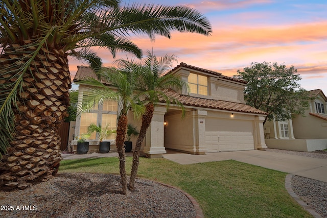 mediterranean / spanish-style house with driveway, stucco siding, a tile roof, and a lawn