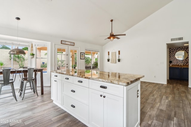 kitchen with light wood finished floors, ceiling fan, vaulted ceiling, french doors, and white cabinets