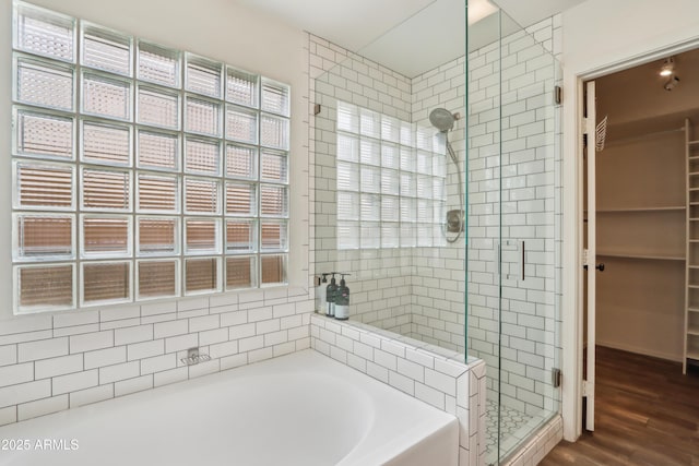 bathroom featuring a shower stall, a bath, wood finished floors, and a walk in closet