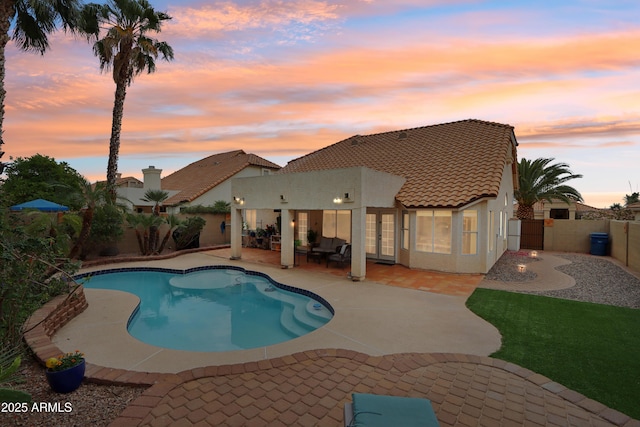 pool at dusk with a fenced backyard, a patio area, and french doors