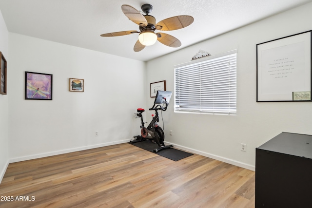 workout room with light wood finished floors, baseboards, and a ceiling fan