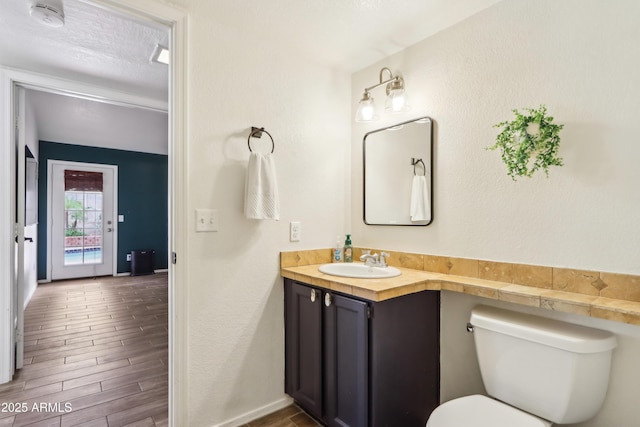 half bathroom featuring wood finished floors, toilet, and vanity
