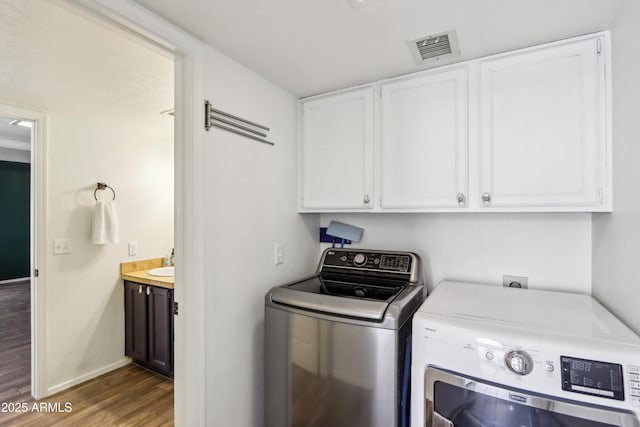 washroom featuring cabinet space, washer and clothes dryer, wood finished floors, and baseboards