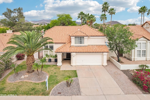 mediterranean / spanish home featuring a tiled roof, a mountain view, driveway, stucco siding, and a front lawn