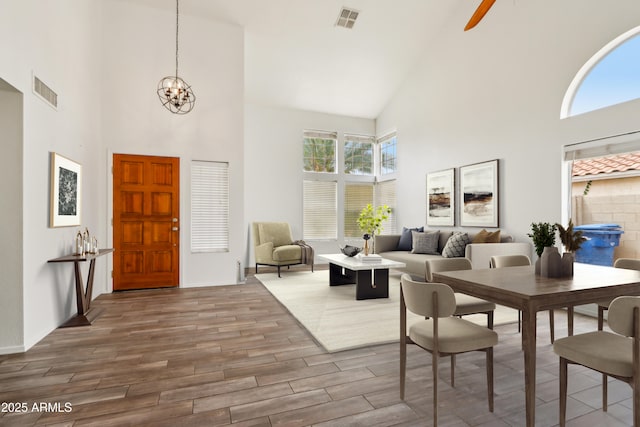 foyer entrance with high vaulted ceiling, a chandelier, wood finished floors, and ceiling fan
