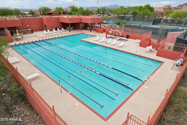 community pool featuring fence, a mountain view, and a patio