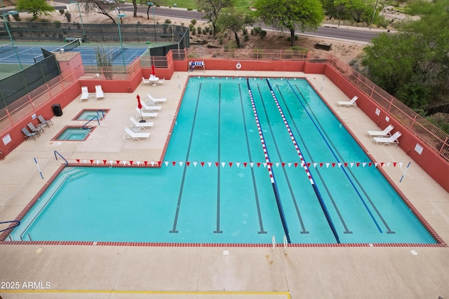 community pool featuring a hot tub, fence, and a patio area