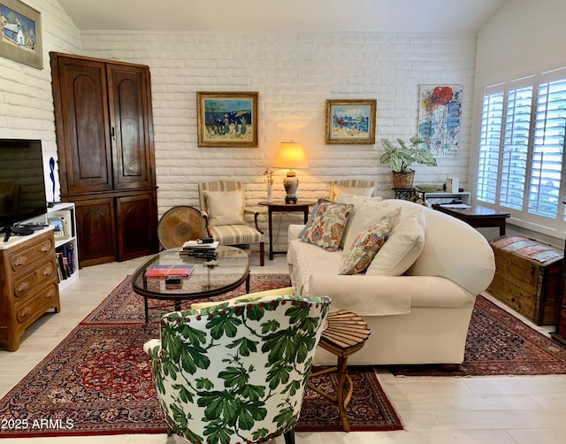 living room with healthy amount of natural light, vaulted ceiling, and brick wall