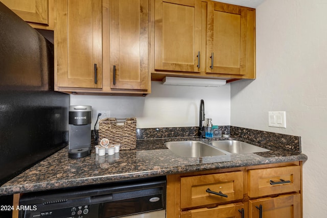 kitchen featuring dark stone countertops, dishwasher, and sink