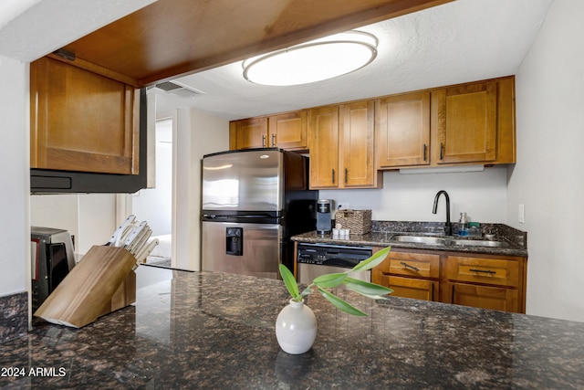 kitchen with stainless steel appliances, dark stone counters, and sink