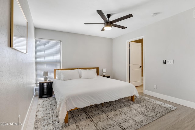 bedroom with ceiling fan, light hardwood / wood-style floors, and connected bathroom