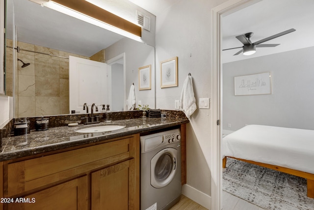 bathroom featuring a tile shower, washer / clothes dryer, ceiling fan, and vanity